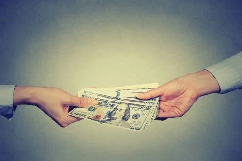 Image of a person handing hundreds of dollars in cash to another